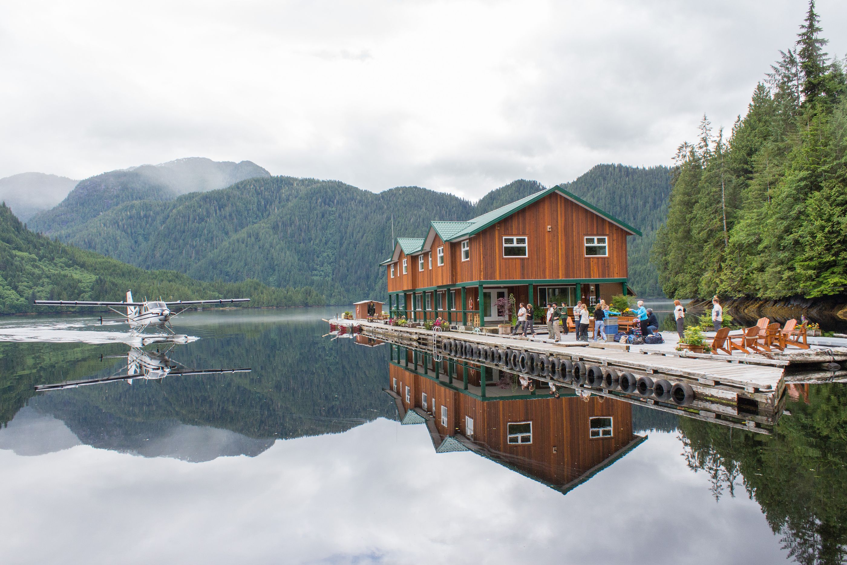 Seaplane Lodge with mountains in background reflecting in water, Great Bear Lodge, Canada