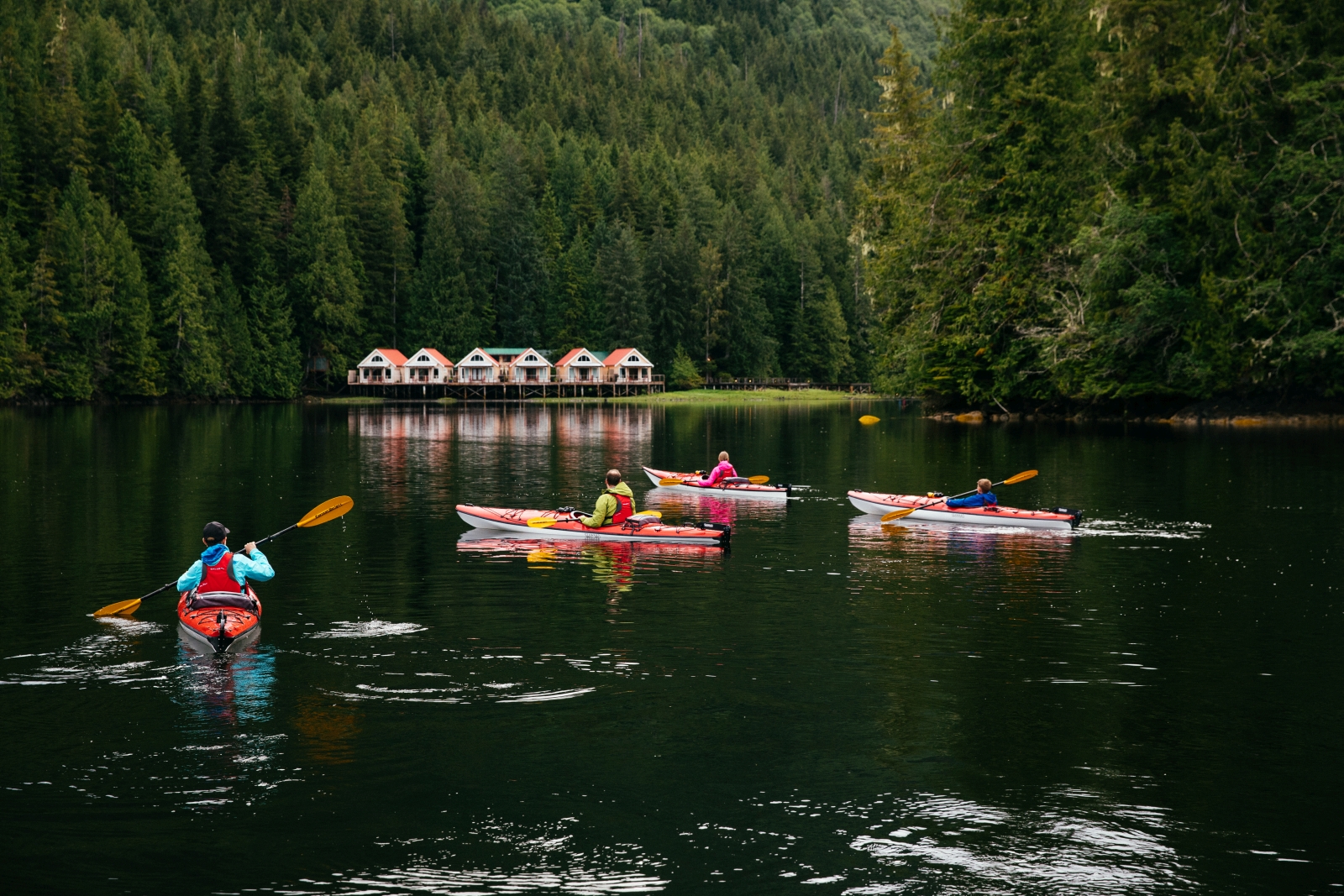 Four guests kayaking in front of luxury hotel Nimmo Bay in Canada