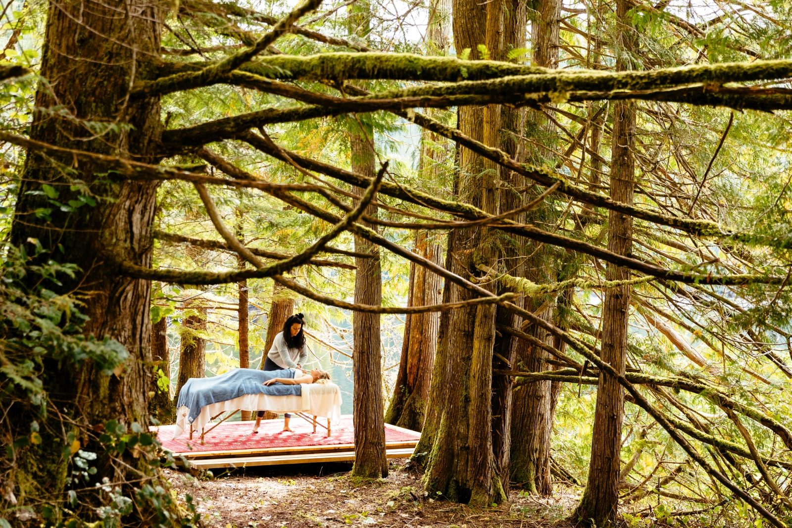 Guest enjoying a massage in the lush green forest at luxury hotel Nimmo Bay in Canada