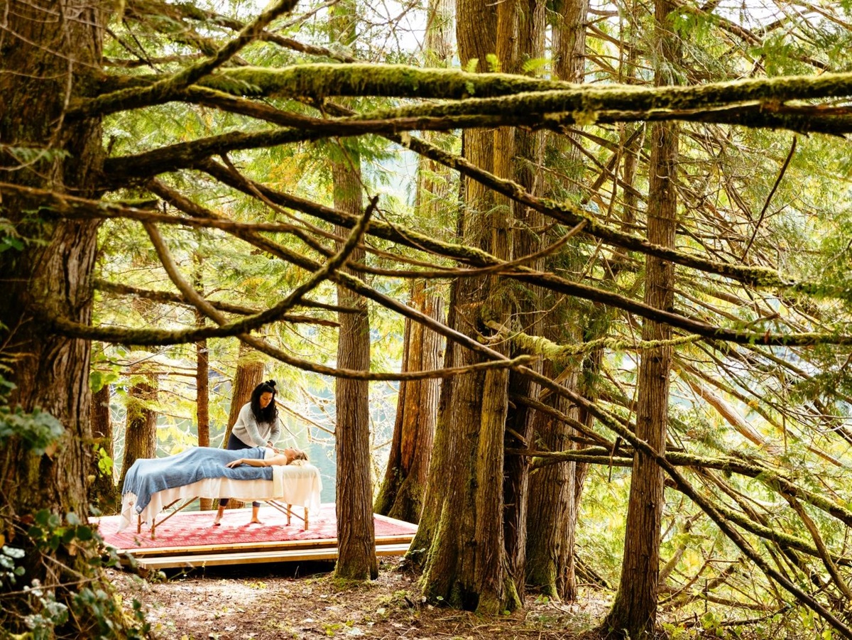 Guest enjoying a massage in the lush green forest at luxury hotel Nimmo Bay in Canada