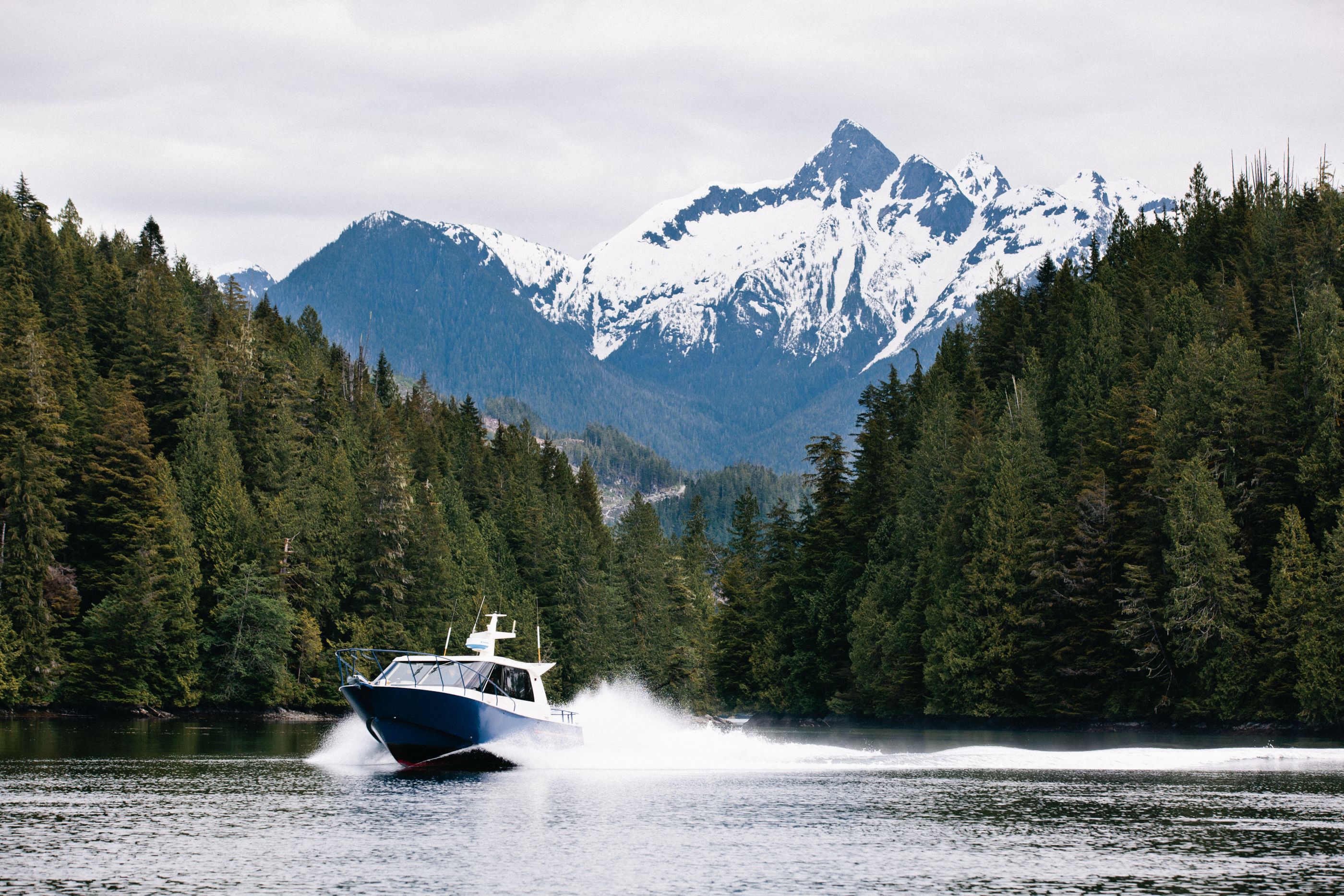 Speedboat with mountains and forest near Nimmo Bay Wilderness Resort, Canada