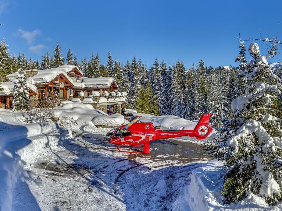 Helicopter landing in front of the snowy luxury villa Belmont Estate in Whistler, Canada