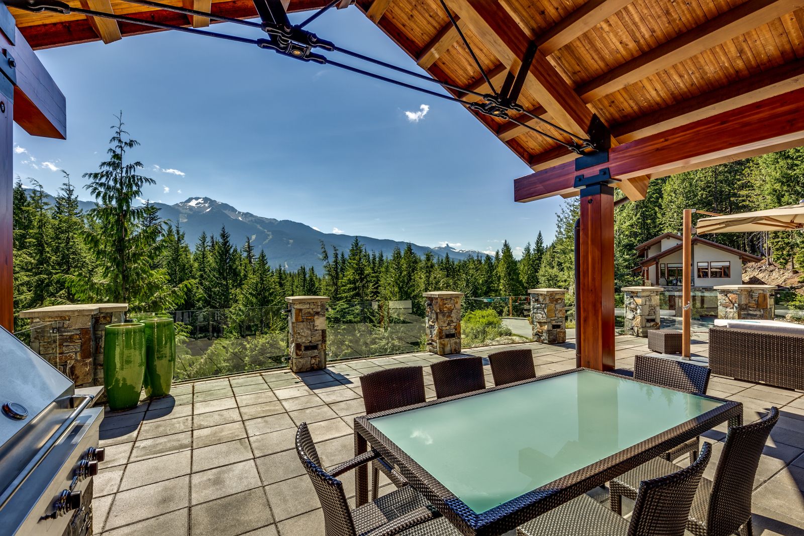 Covered terrace with outdoor dining and BBQ overlooking the mountains at luxury private home The Belmont Estate in Whistler, Canada