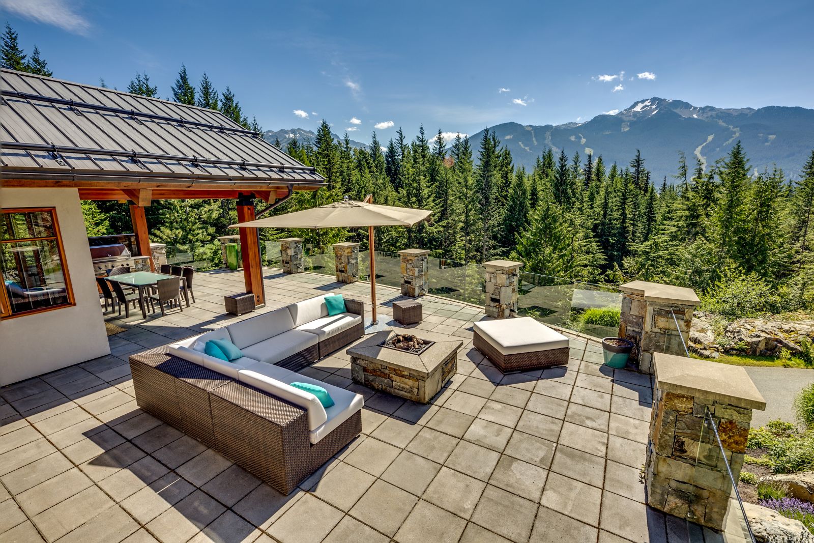 View over the mountains from the terrace with lounging area and fire pit at luxury private home The Belmont Estate in Whistler, Canada