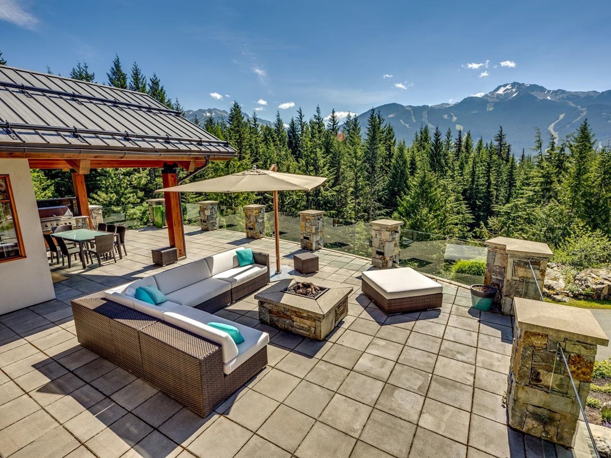 View over the mountains from the terrace with lounging area and fire pit at luxury private home The Belmont Estate in Whistler, Canada