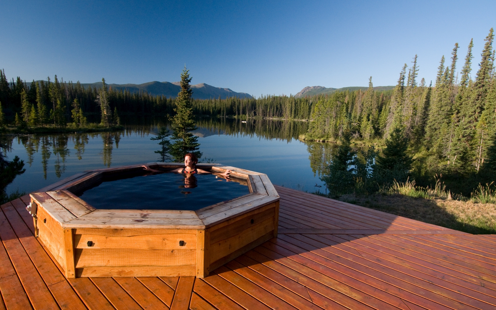 Hot tub on a wooden deck with a lake behind it