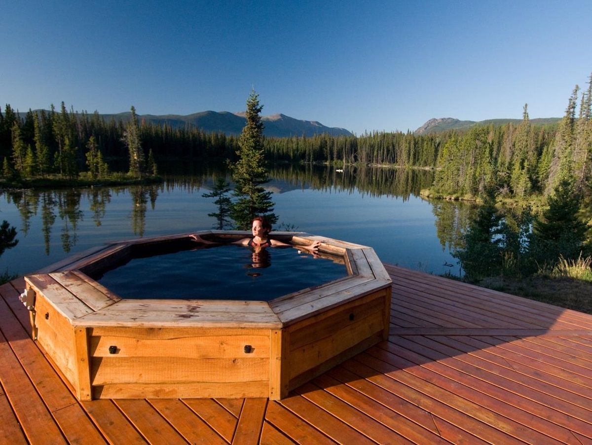 Hot tub on a wooden deck with a lake behind it