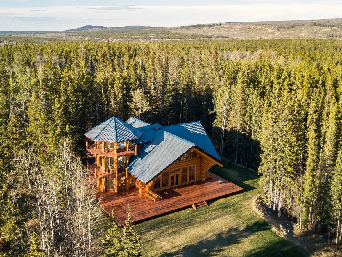 Aerial view of large tower house amidst green pine forrest