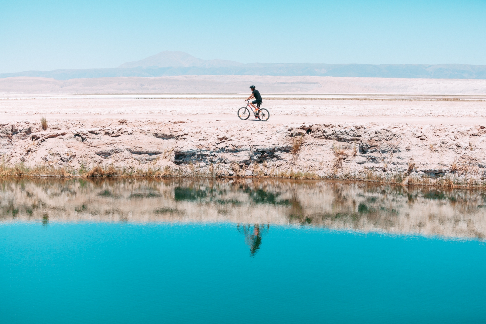 Cyclist reflected in a lake in the desert