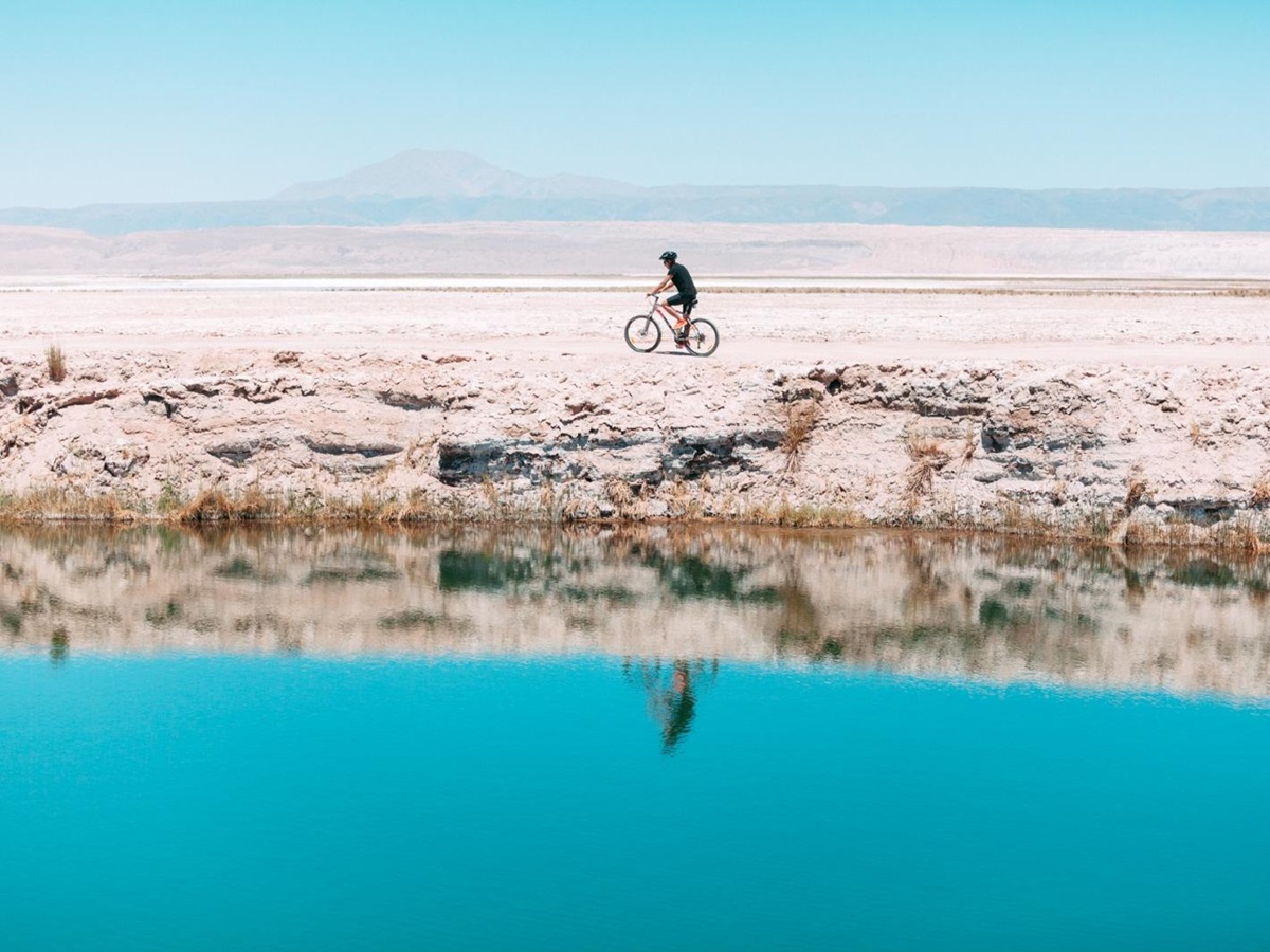Cyclist reflected in a lake in the desert