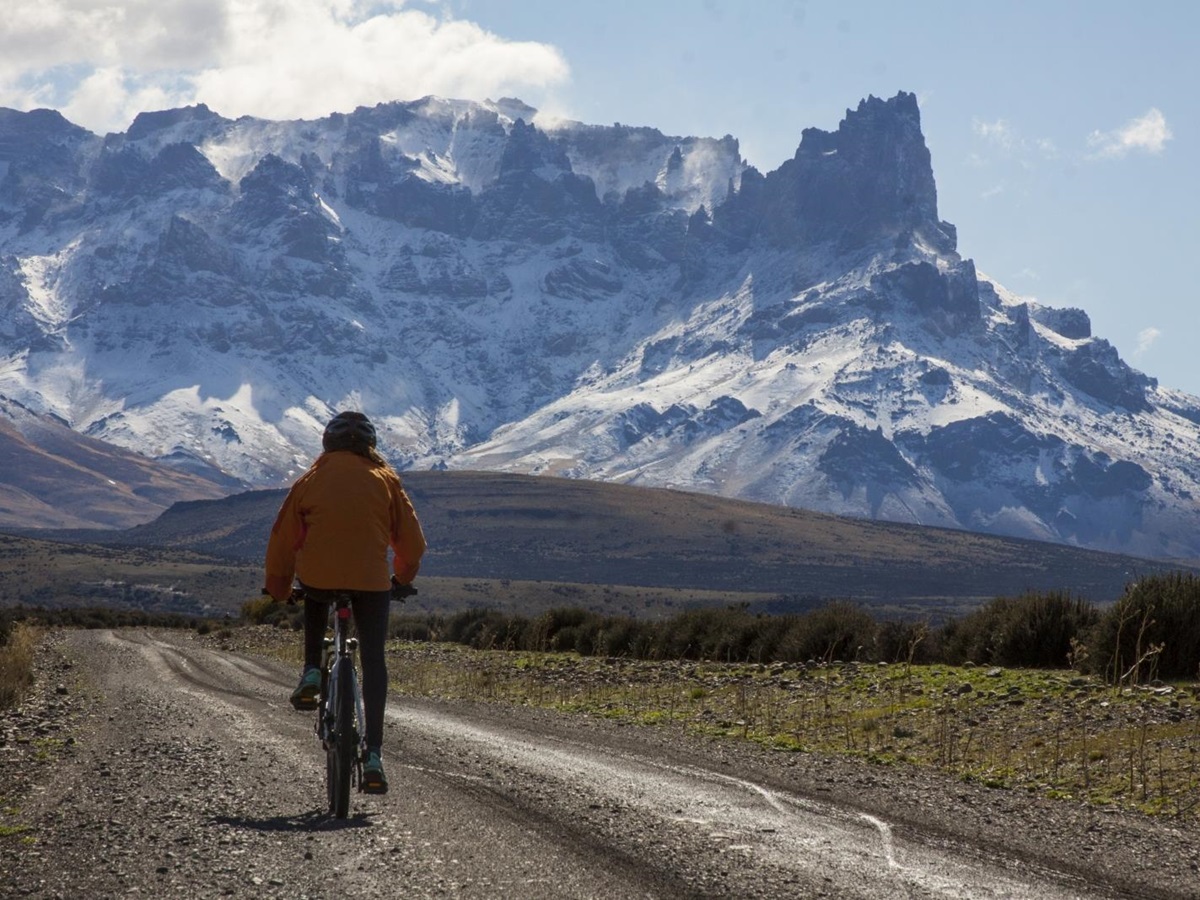 Cyclist riding towards snowy mountains