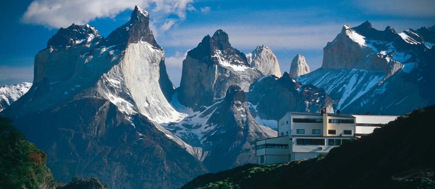 Exterior of Explora Patagonia with impressive mountain range and waterfall