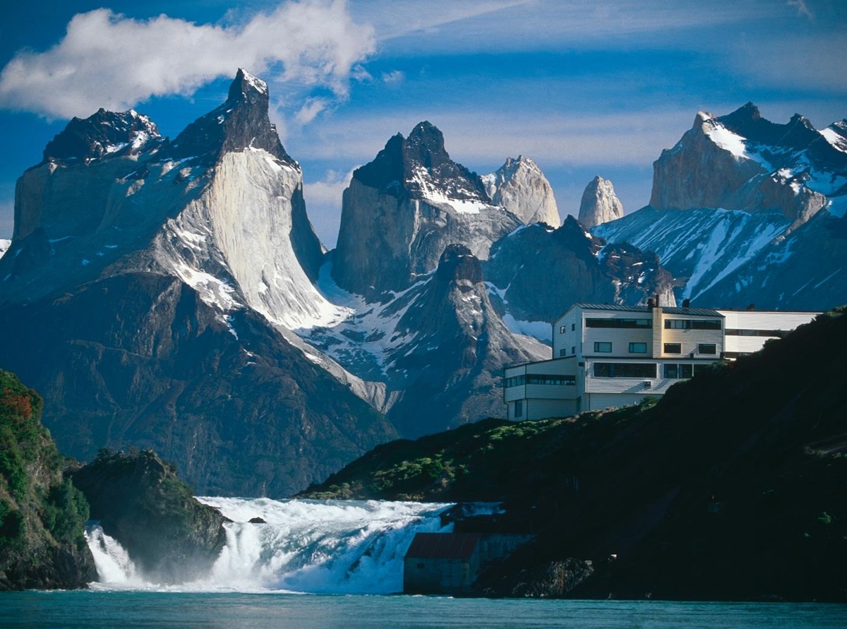 Exterior of Explora Patagonia with impressive mountain range and waterfall