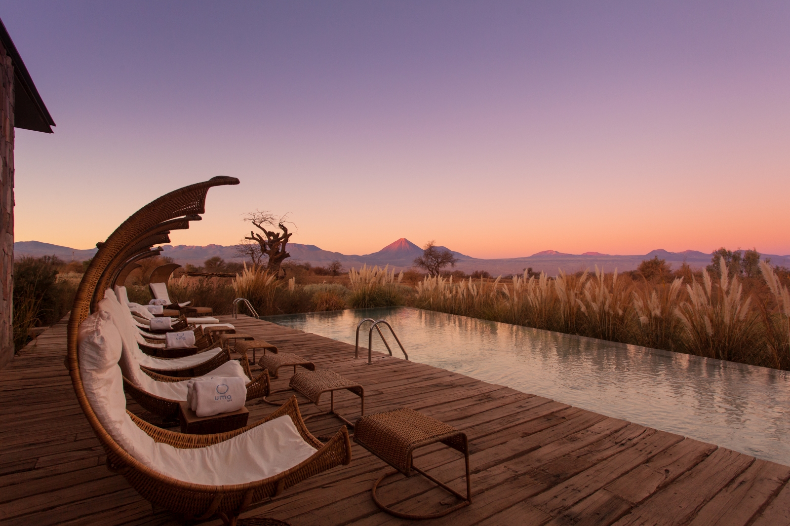 Loungers standing next to the pool at dusk, with views over the desert and moutnains