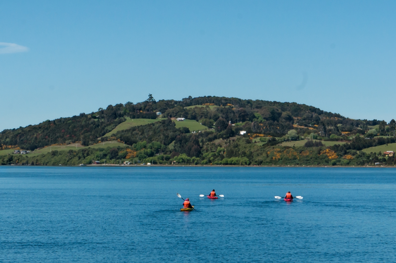three people kayaking on a lake