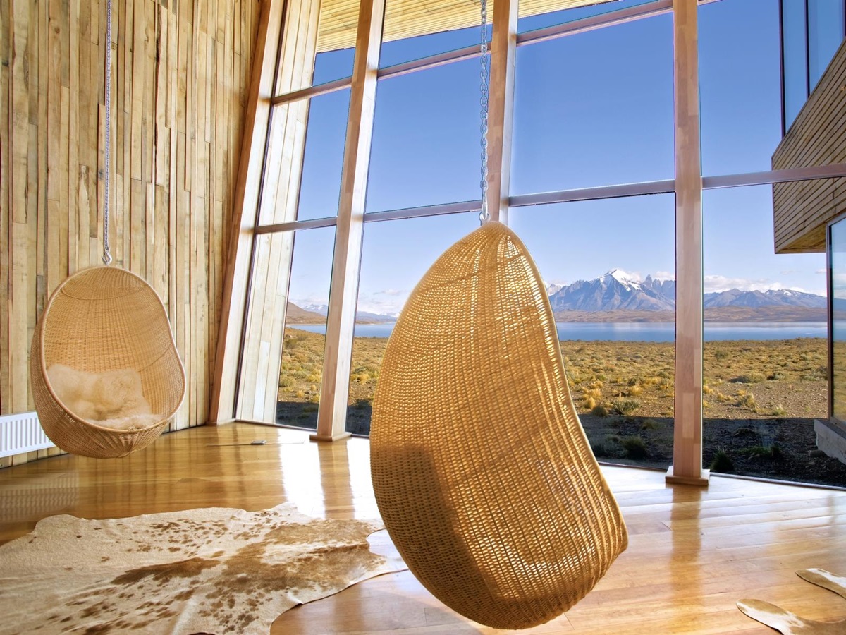 Two hanging chair egg chairs in front of a glasss wall overlooking the scenery at Tierra Patagonia