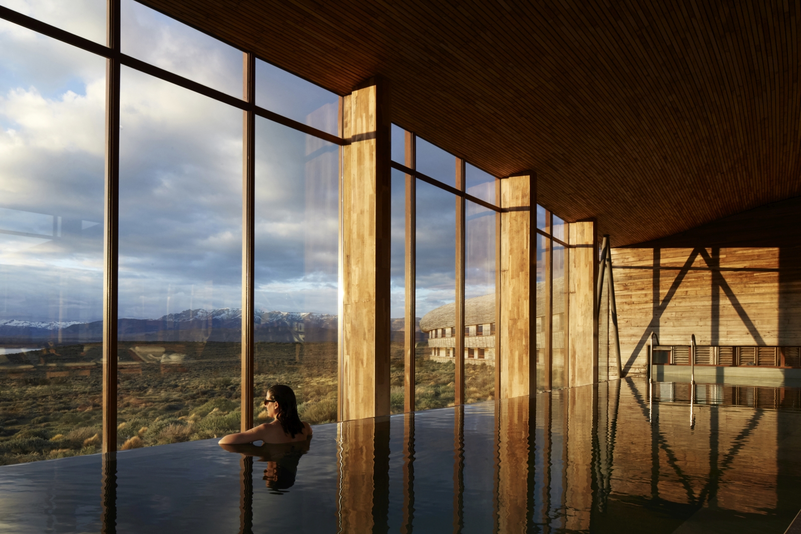 woman in an indoor pool enjoying the scenery through floor to ceiling windows