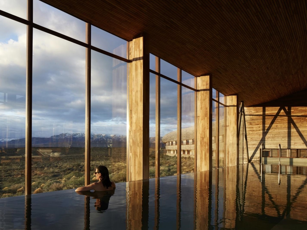 woman in an indoor pool enjoying the scenery through floor to ceiling windows