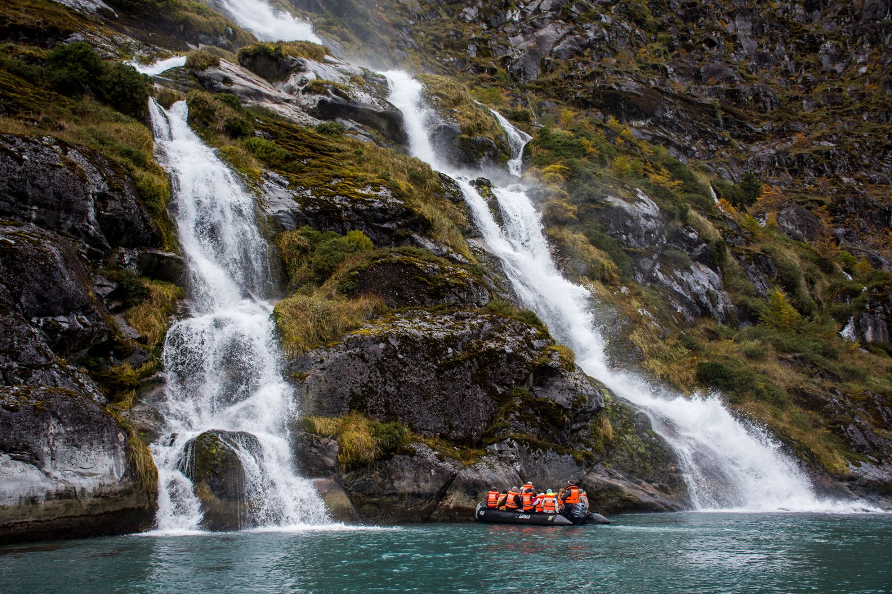 Guests of the the Stella Australis Patagonia observing waterfalls from a Zodiac