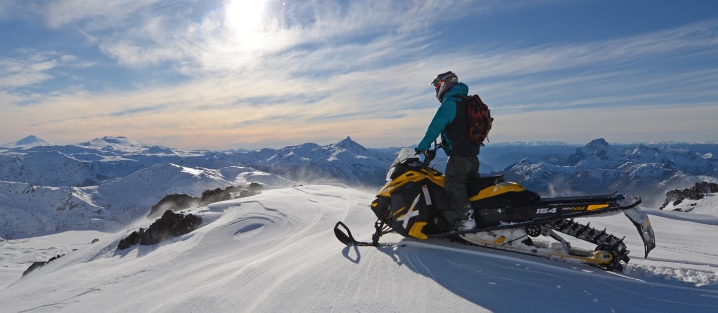 person on snowmobile looking over the mountains
