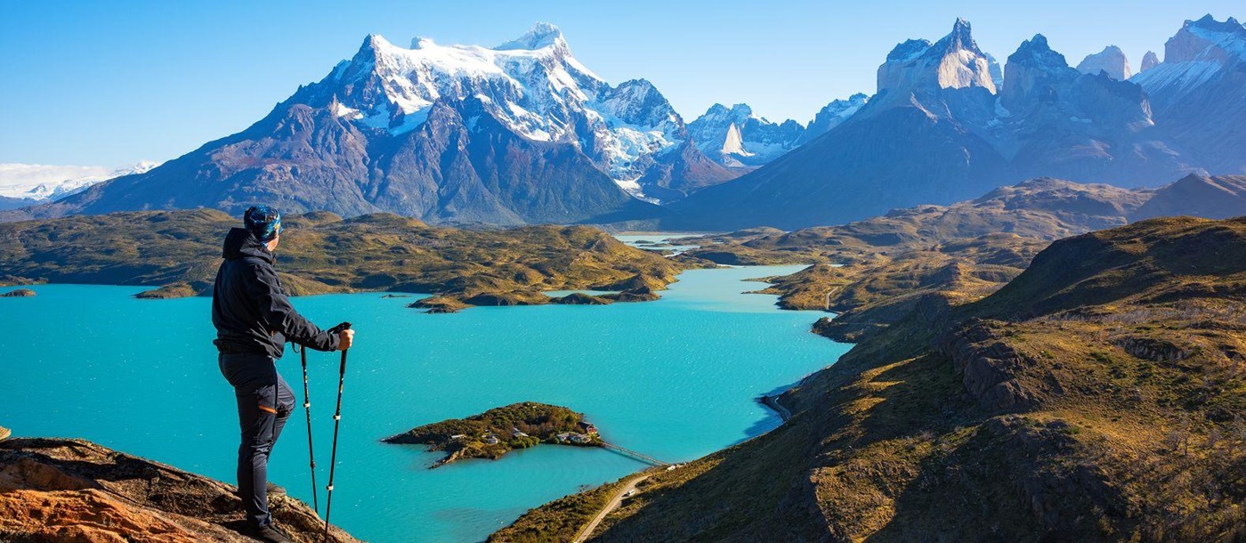 A hiker looking out over a dazzling turquoise lake and the Torres del Paine horns in Patagonia Chile