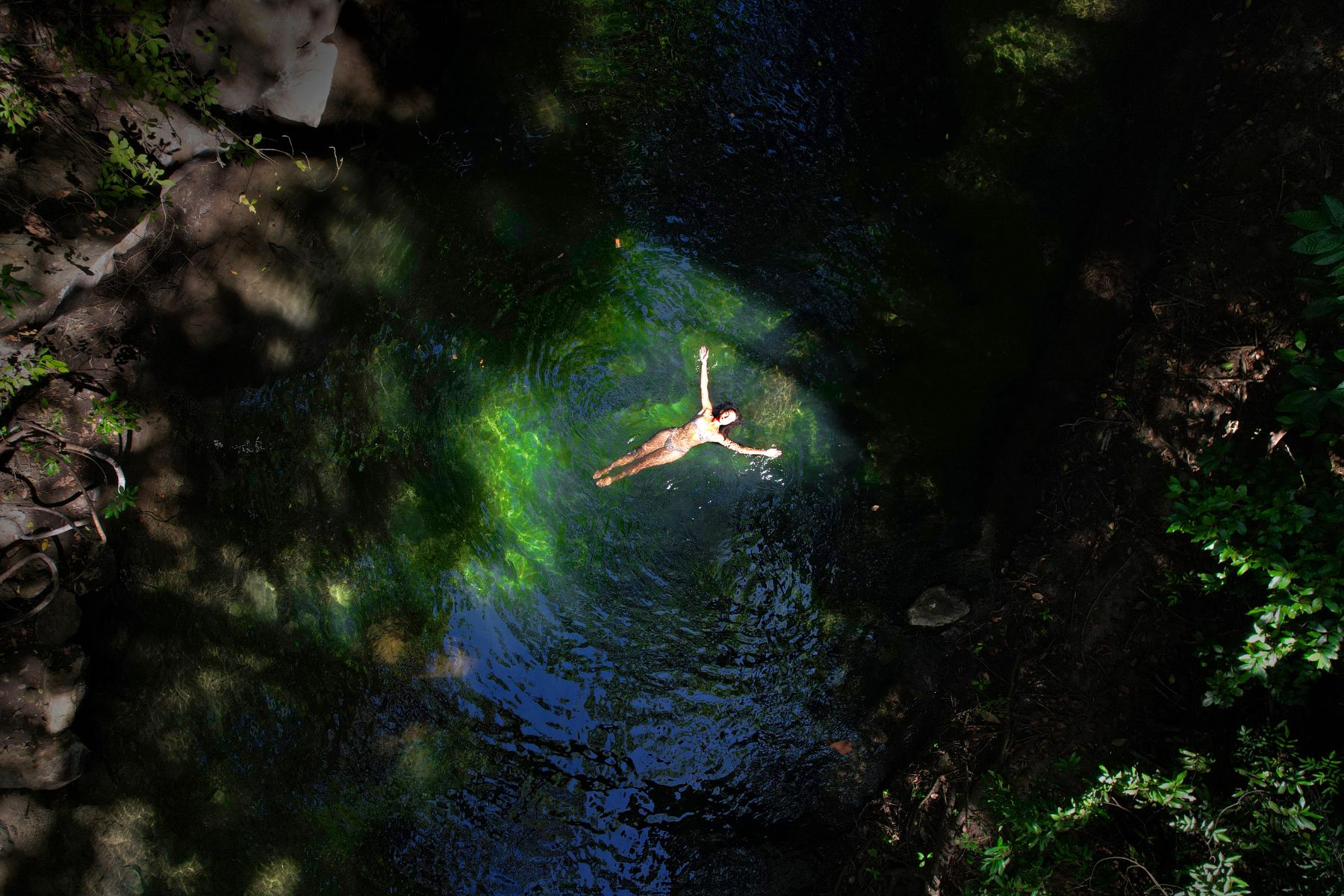 Lady floating in a crystal clear river at Rio Perdido in Costa Rica
