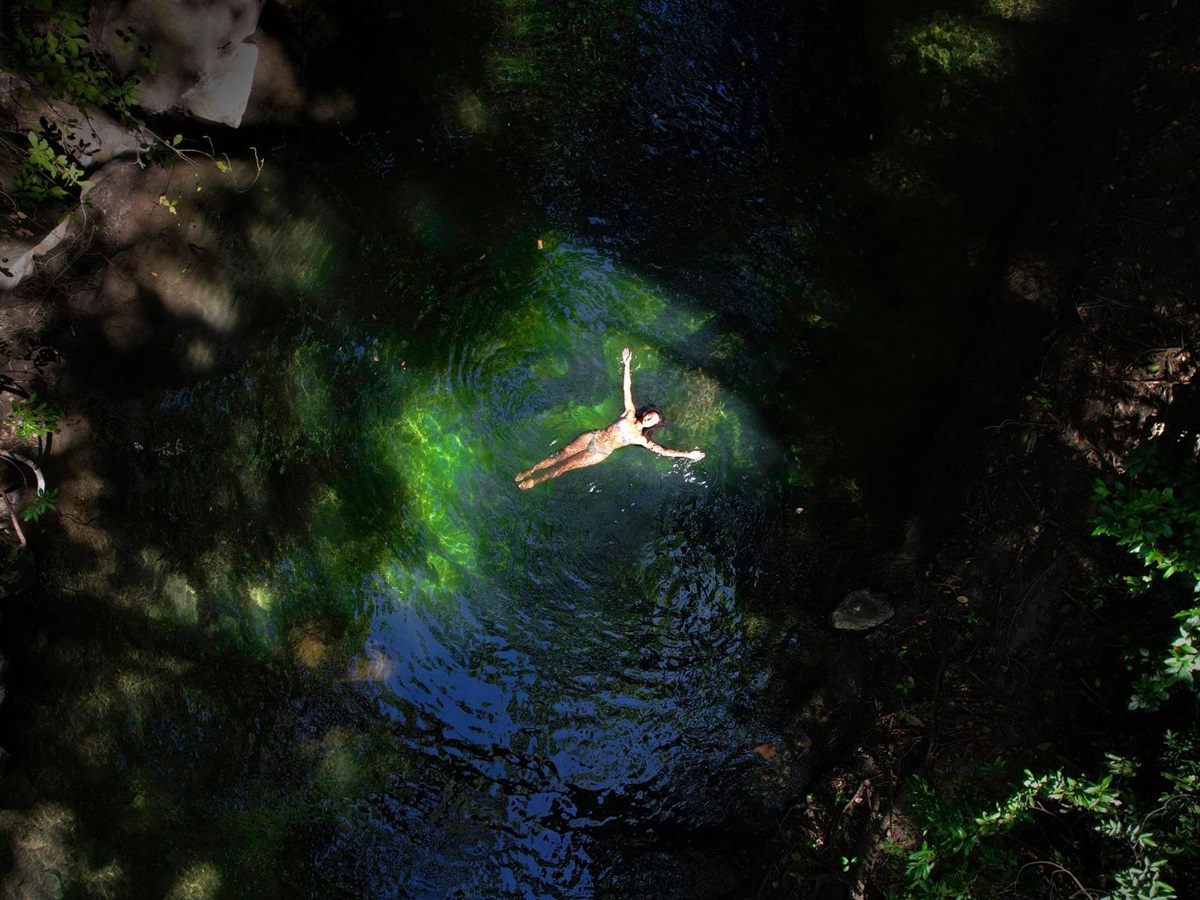 Lady floating in a crystal clear river at Rio Perdido in Costa Rica
