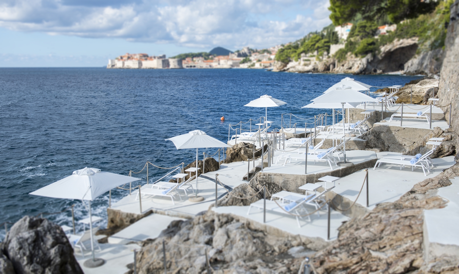 Seaside cliff with terraces for sunloungers and parasols at luxury hotel Villa Dubrovnik in Croatia