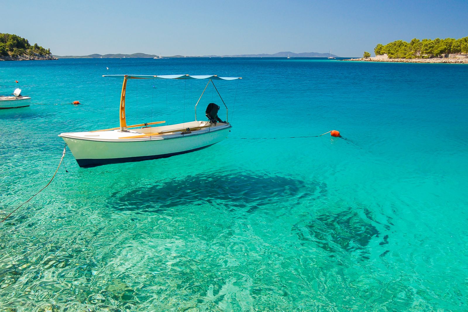 A small fishing boat reflected in crystal clear waters in Milna Bay, Brač Island, Croatia