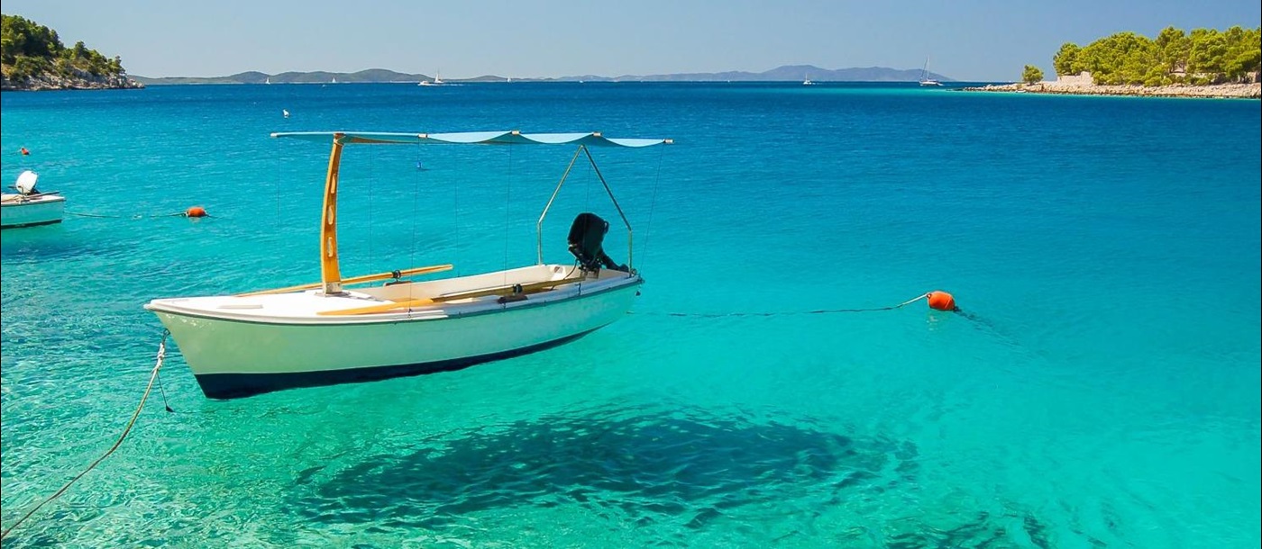 A small fishing boat reflectedin crystal clear waters in Milna Bay Brac Island Croatia