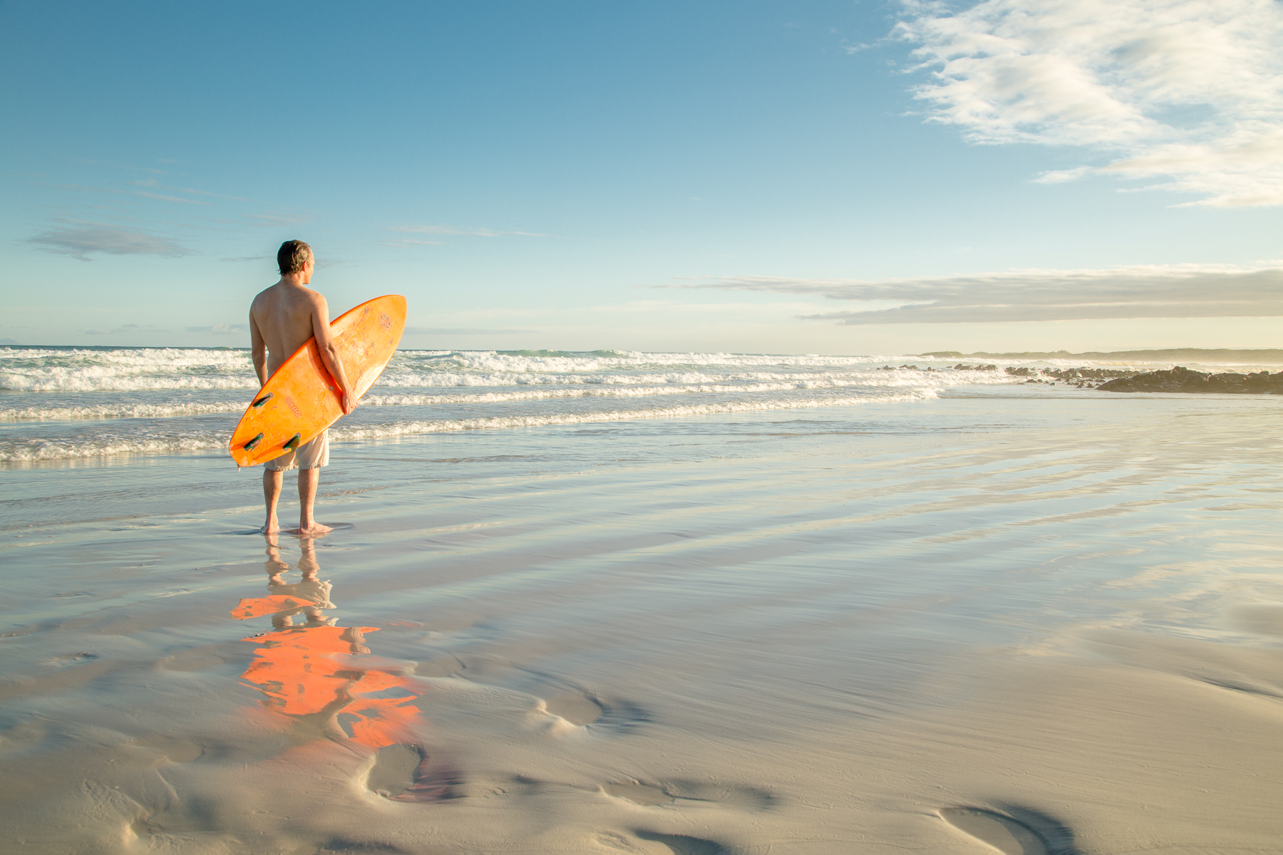 A surfer on the beach at Finch Bay in the Galapagos Islands