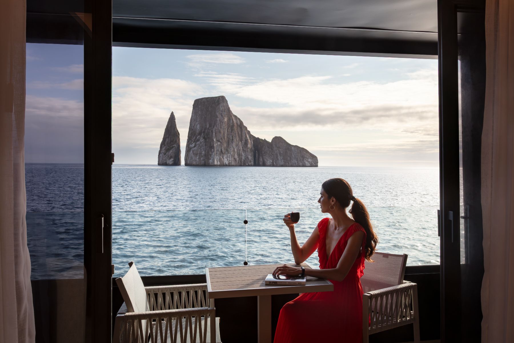 Guest enjoying her private balcony and Kicker Rock view on the Hermes Galapagos luxury catamaran