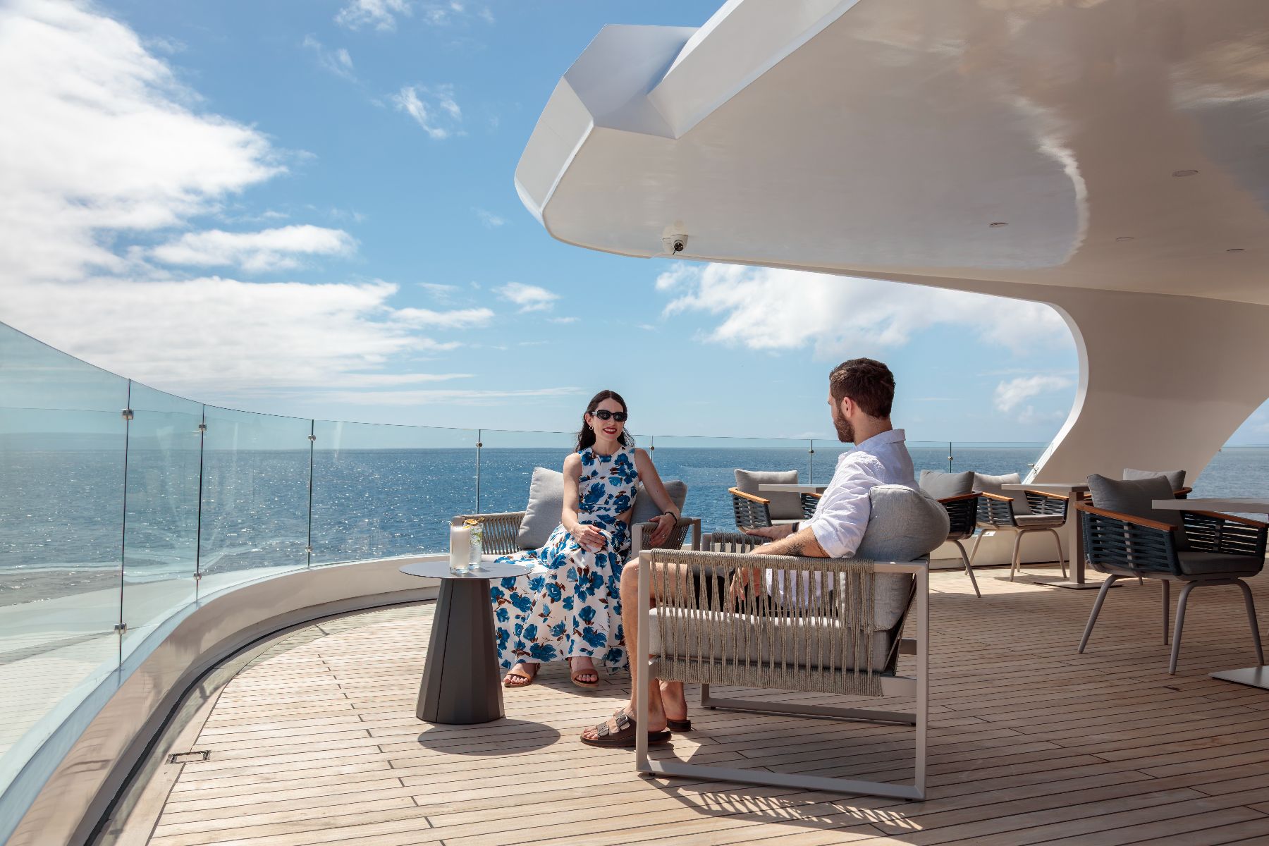 Guests of Hermes Galapagos luxury catamaran enjoying drinks on deck on one of the many outdoor terraces