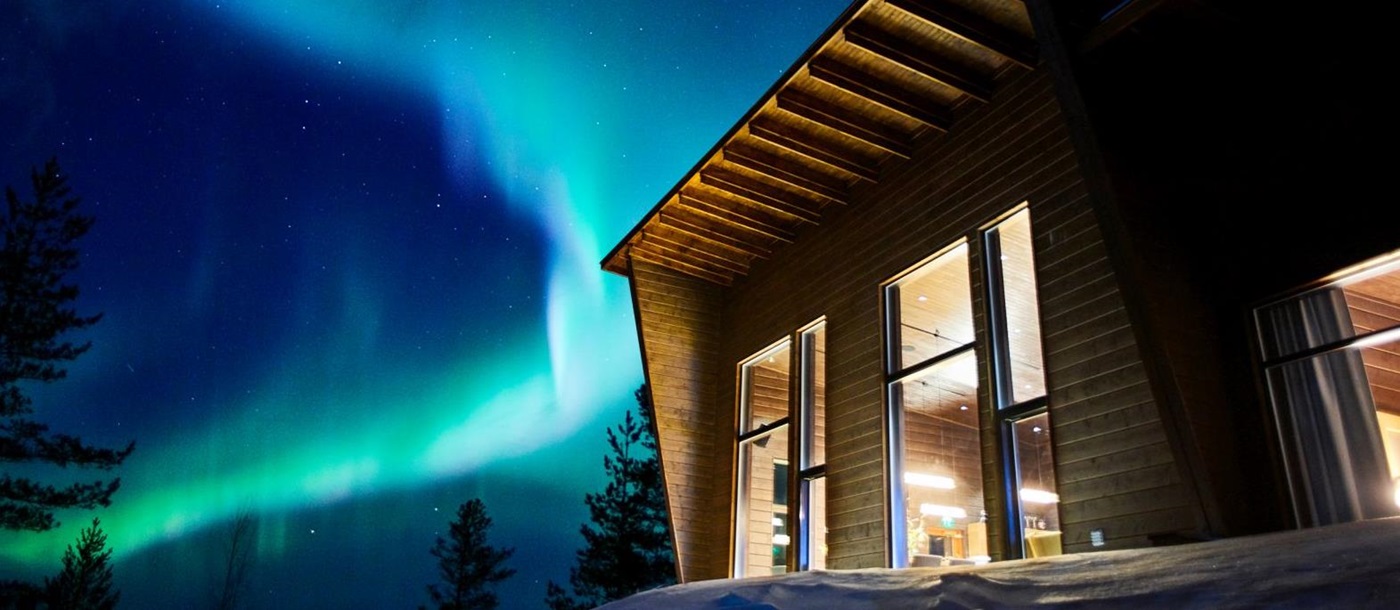 The Northern Lights shining over Octola wilderness lodge in Finland