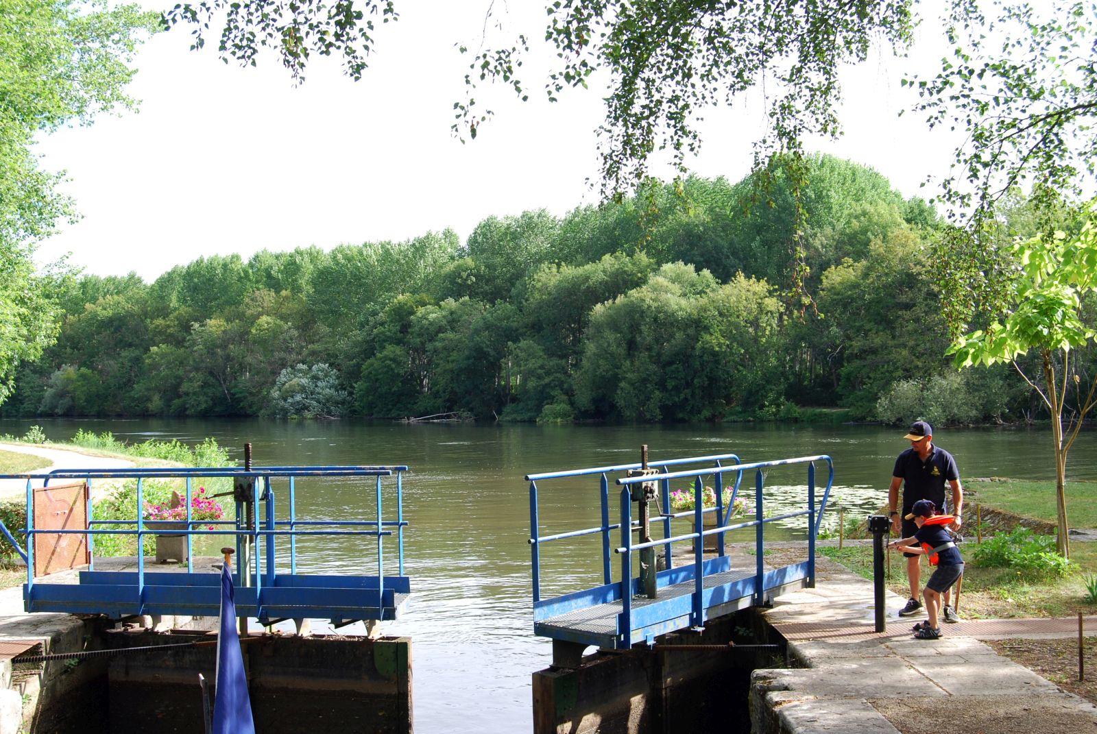 Father and child opening the locks on the Enchante canal cruise in France