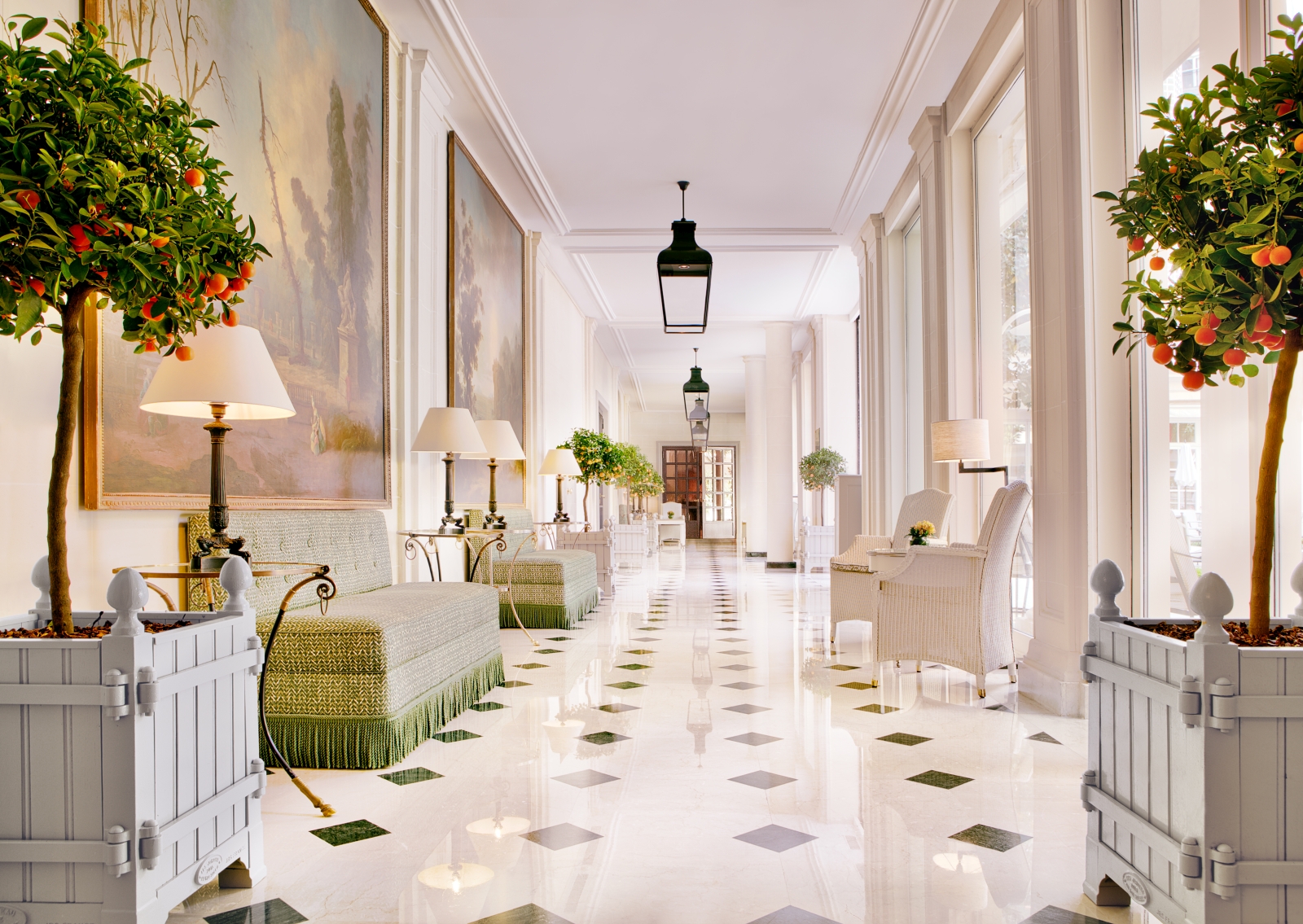 Grande hallway with peach trees and wall-covering pieces of art at luxury hotel Le Bristol in Paris, France