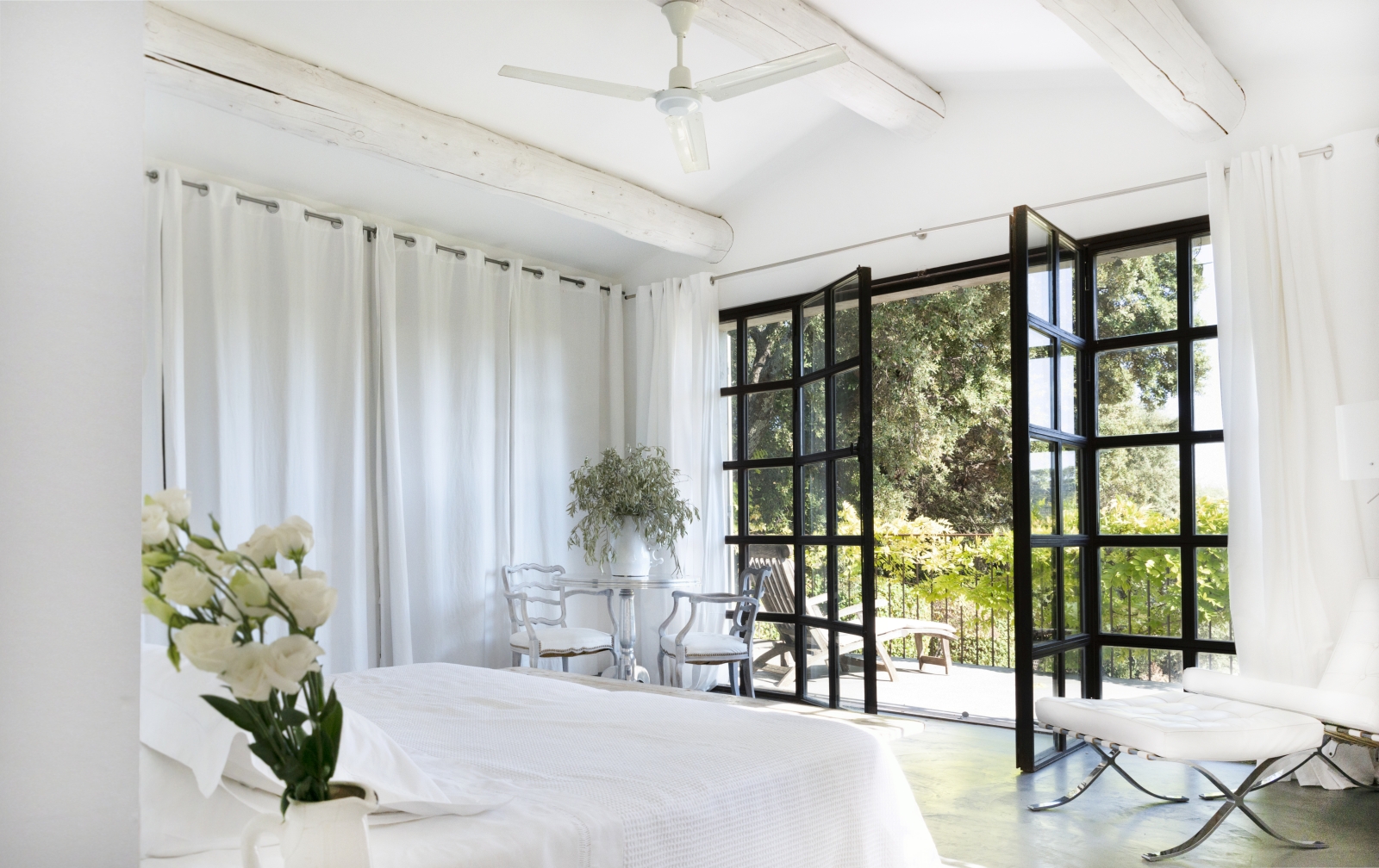 Bedroom with double bed, flowers, table, chairs, plant and French doors to balcony at La Cadiere on the Cote d’Azur, France