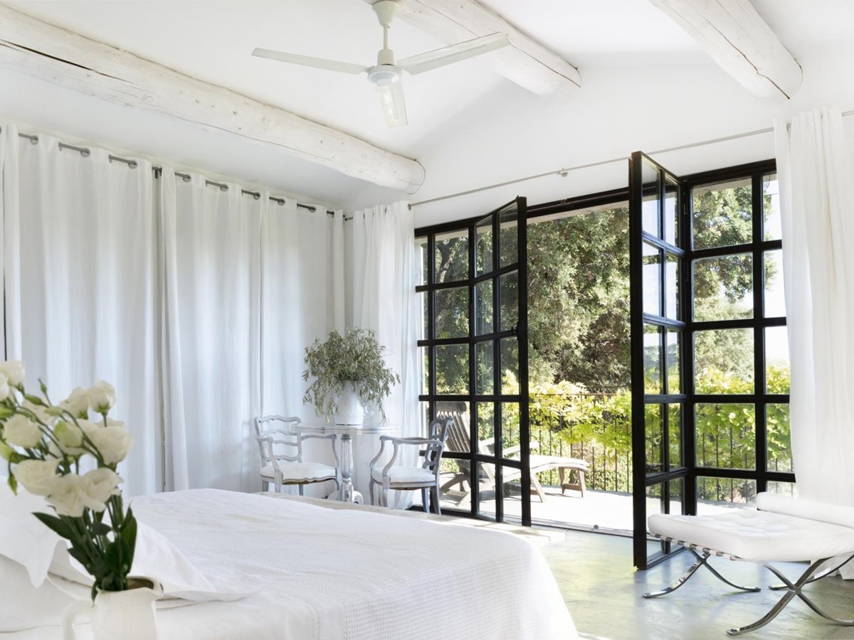 Bedroom with double bed, flowers, table, chairs, plant and French doors to balcony at La Cadiere on the Cote d’Azur, France