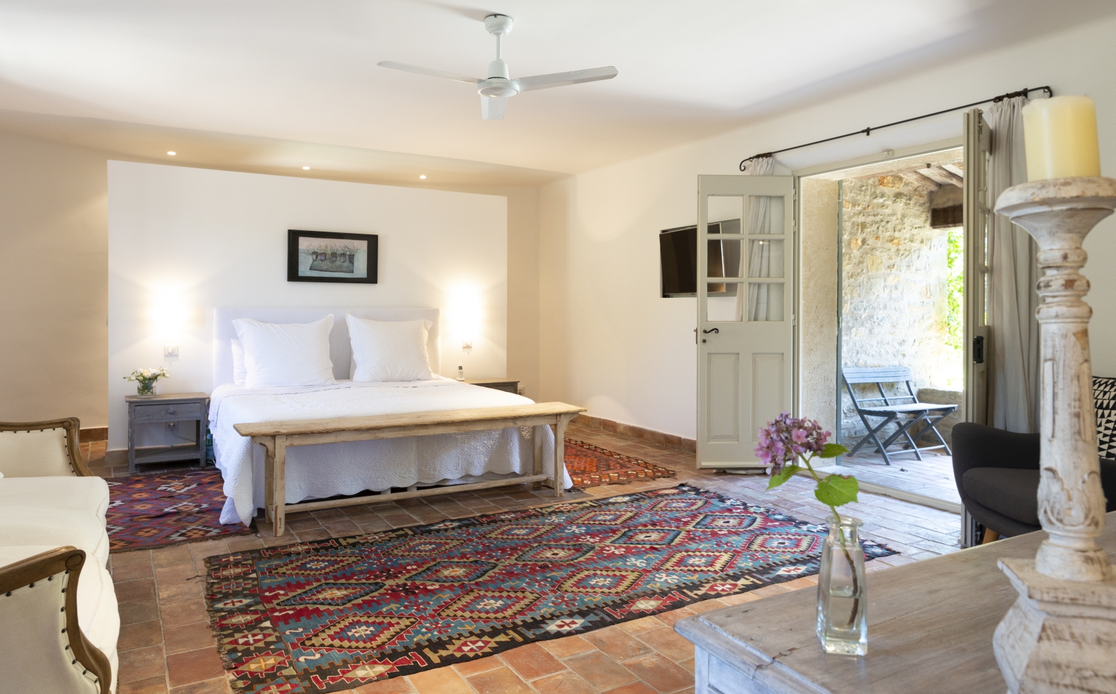 Master bedroom with double bed, sofa, flower, candle, patterned rug and French doors at La Cadiere on the Cote d’Azur, France