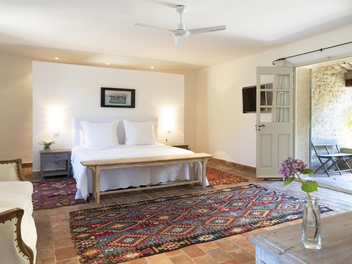 Master bedroom with double bed, sofa, flower, candle, patterned rug and French doors at La Cadiere on the Cote d’Azur, France