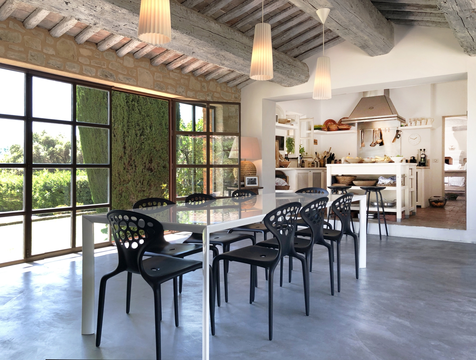 Dining area next to kitchen with table, chairs, hanging lights and French doors at La Cadiere on the Cote d’Azur, France