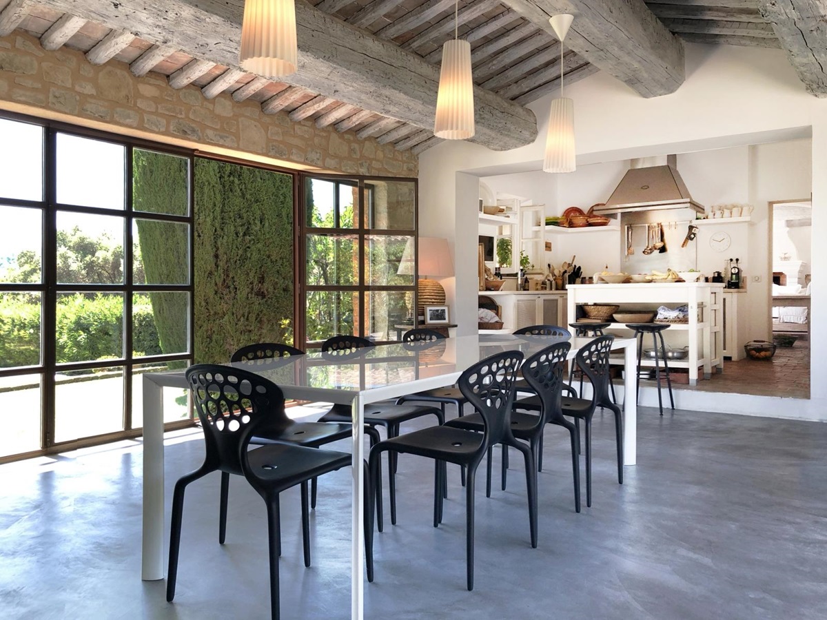 Dining area next to kitchen with table, chairs, hanging lights and French doors at La Cadiere on the Cote d’Azur, France