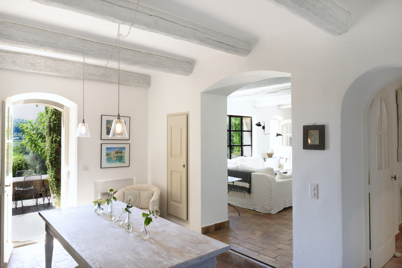 Entrance hallway with table, flowers, hanging light and archway to living room at La Cadiere on the Cote d’Azur, France