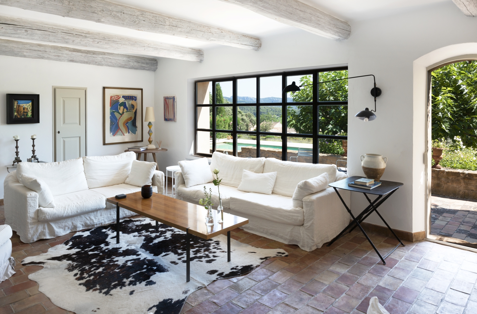 Living room with sofas, tables, lamps, flowers, artwork, rug and pool view at La Cadiere on the Cote d’Azur, France
