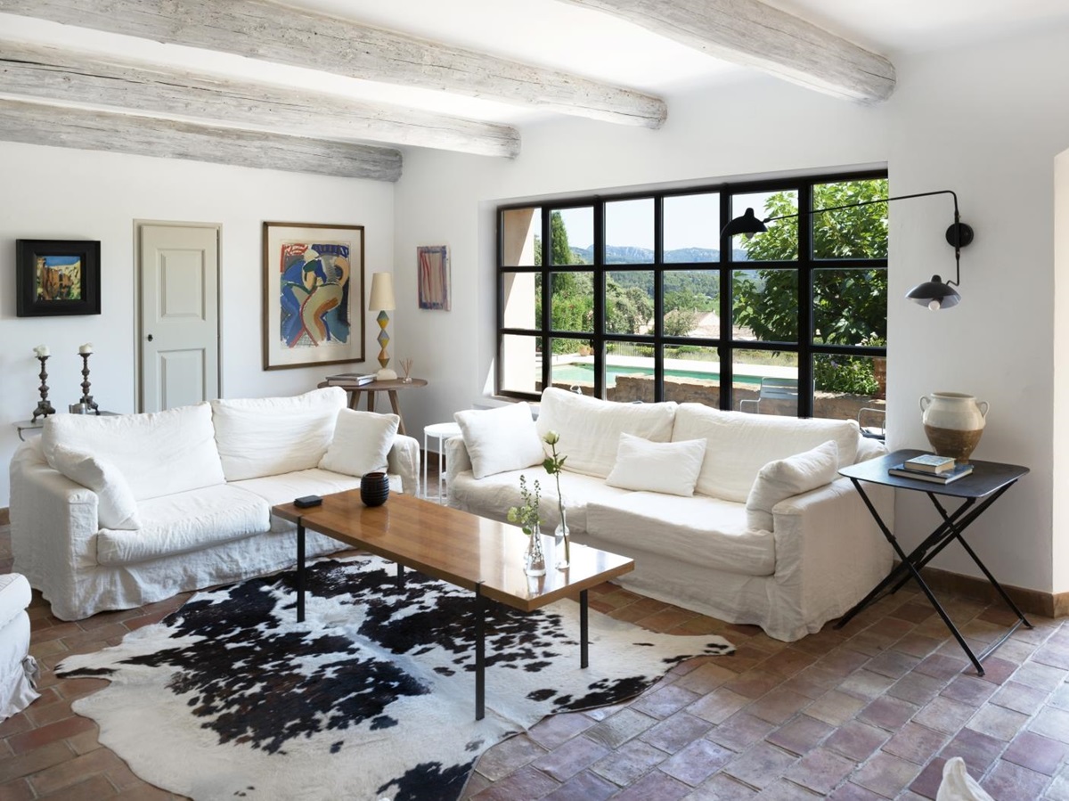Living room with sofas, tables, lamps, flowers, artwork, rug and pool view at La Cadiere on the Cote d’Azur, France