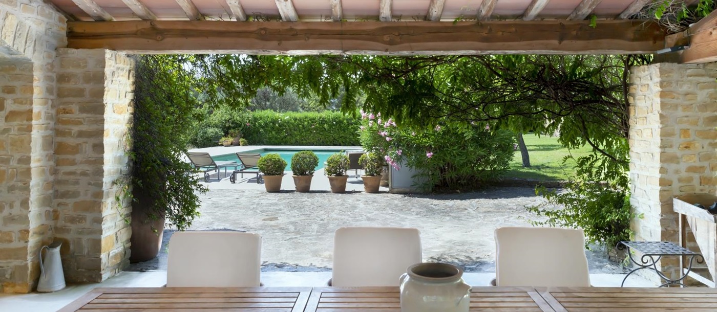 Covered outdoor dining area with table, chairs, vase, ceiling fan and pool view at La Cadiere on the Cote d’Azur, France
