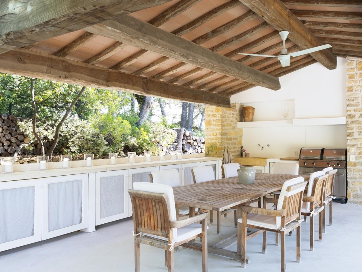 Covered outdoor dining area with table, chairs, candles, BBQ and ceiling fan at La Cadiere on the Cote d’Azur, France