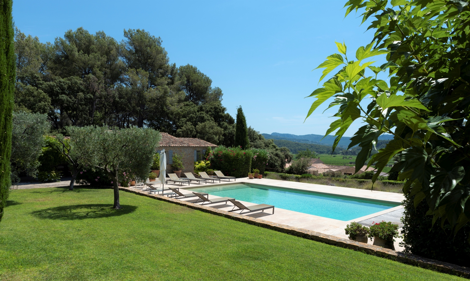 Garden, pool and pool area with sun loungers, umbrellas, plants and countryside view at La Cadiere on the Cote d’Azur, France