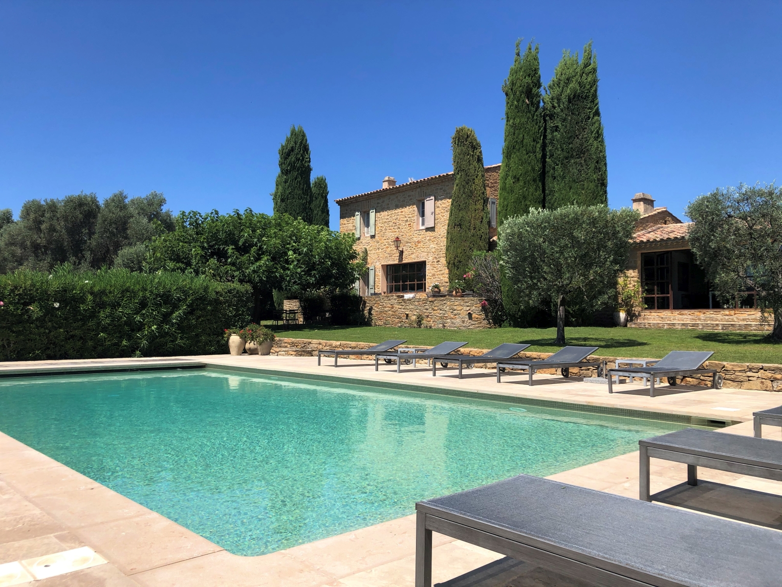 Pool and pool area with sun loungers, flowers & view of house & garden with trees at La Cadiere on the Cote d’Azur, France