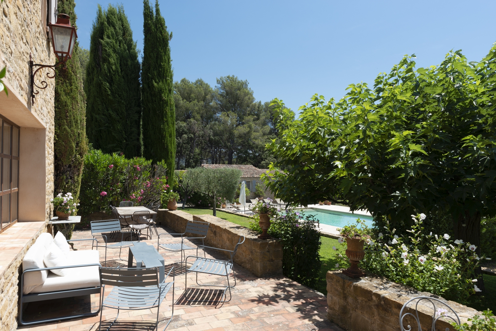 Terrace with sofa, tables, chairs, flowers and pool view at La Cadiere on the Cote d’Azur, France